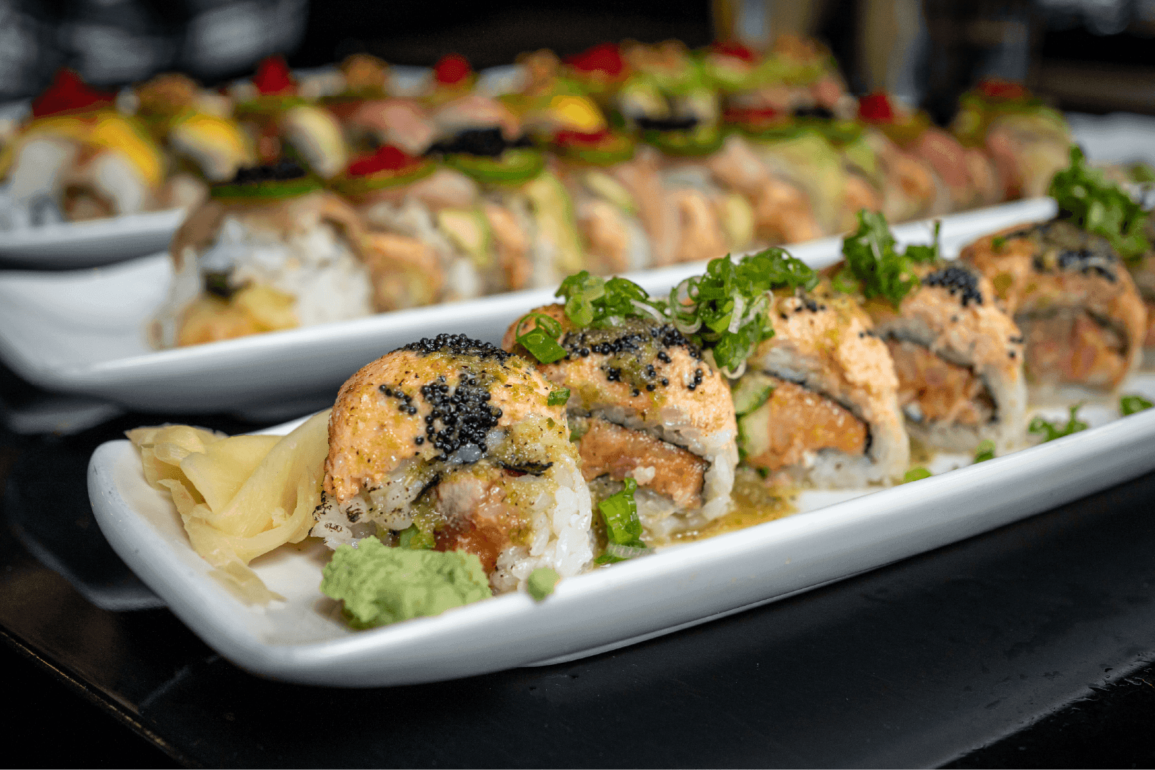 Picture of a Verde la Masa sushi roll. Spicy yellowtail, jalapeno, cilantro, gobo, topped with 7 spice tuna, tomatillo salsa, and pico.