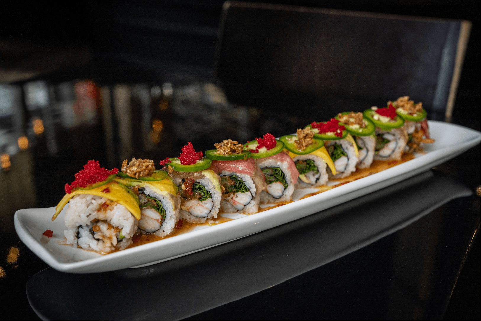 Hawaiian Girlfriend roll. Spicy yellowtail, sea asparagus, avocado, topped with tuna and salmon, ogo, sesame, garlic, chili, and a jalapeno citrus sauce
